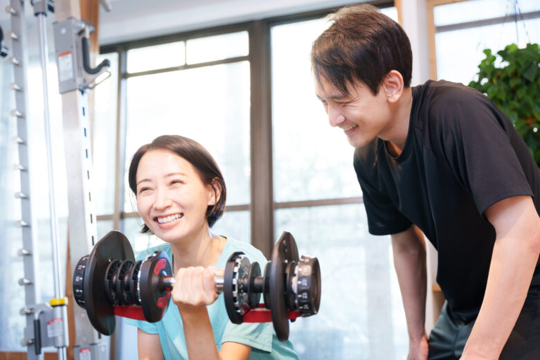 男性トレーナーにサポートしてもらっている女性の写真