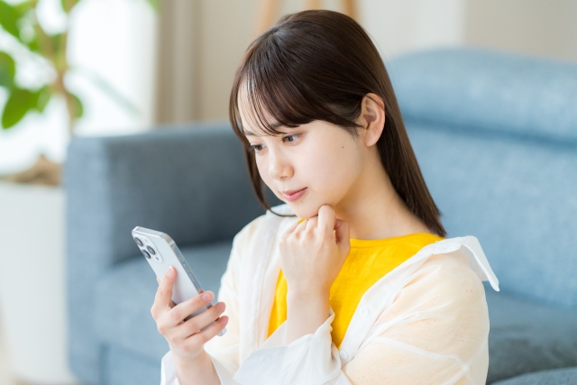 携帯を見て悩んでいる女性